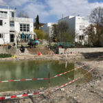 Voller Teich und fertige Trockensteinmauer im Hintergrund im Frühling 2021.